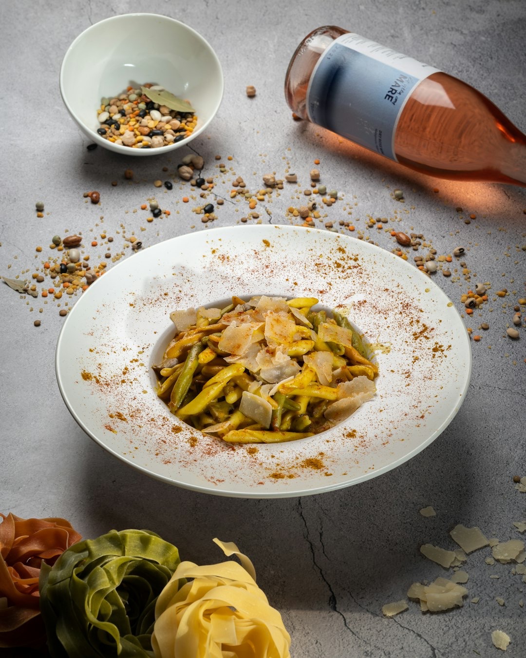 Overhead view of pasta dish with uncooked ingredients and rosé wine.